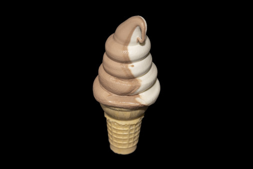 A boy holding a pink and yellow ice cream cone.