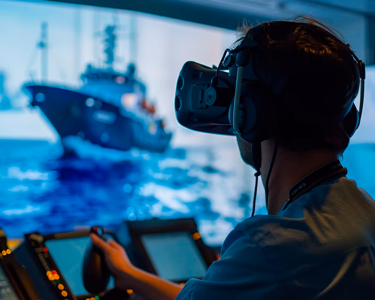 A man in a VR headset at a control centre using a joystick with a ship in the background