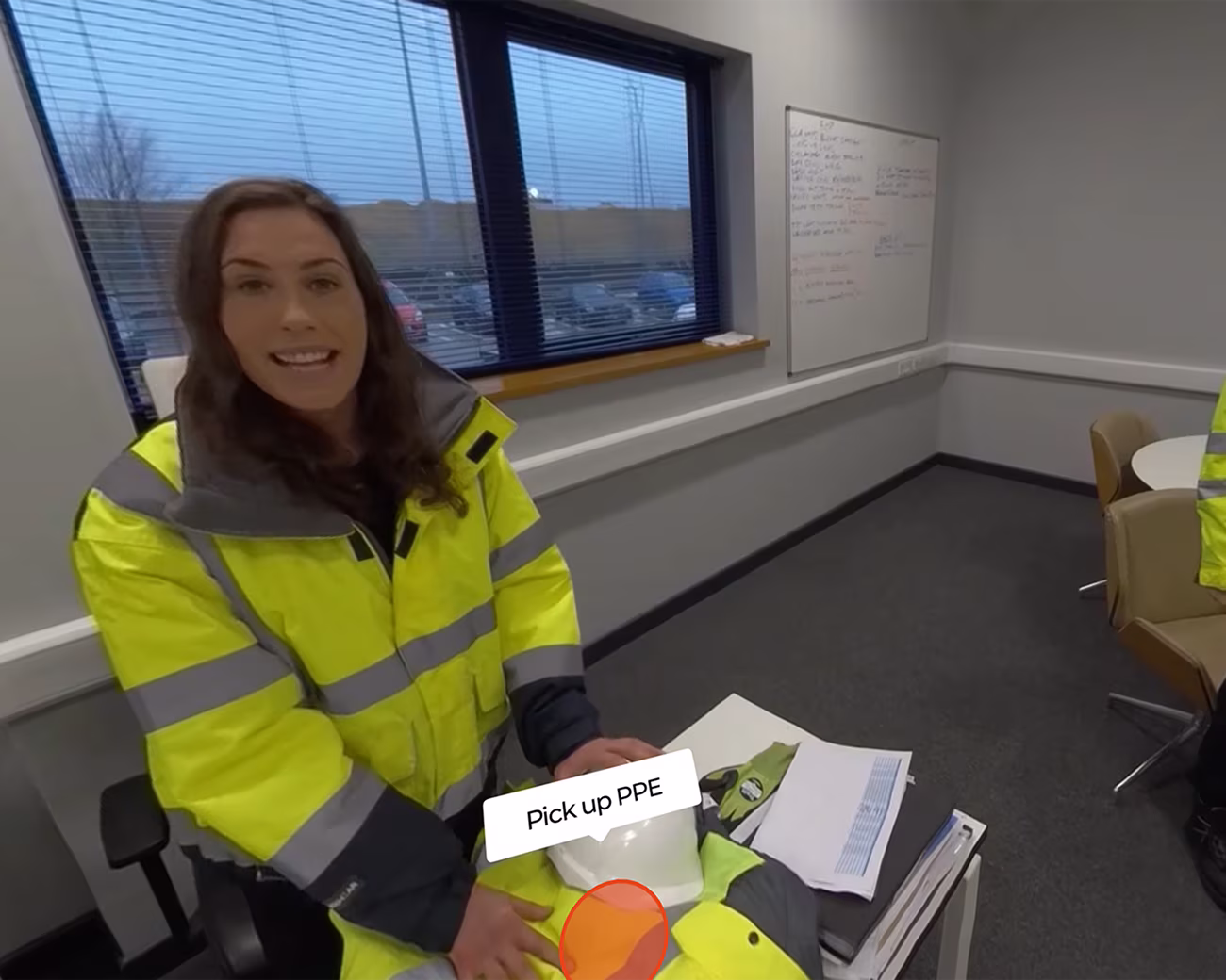 Still image from an emergency evacuation VR training simulation where a supervisor and colleague have greeted the user, and there's an interactive action for the user to "pick up PPE"