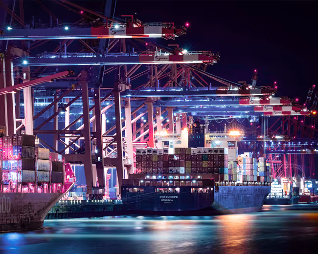 A cargo ship in a lit up port at nighttime