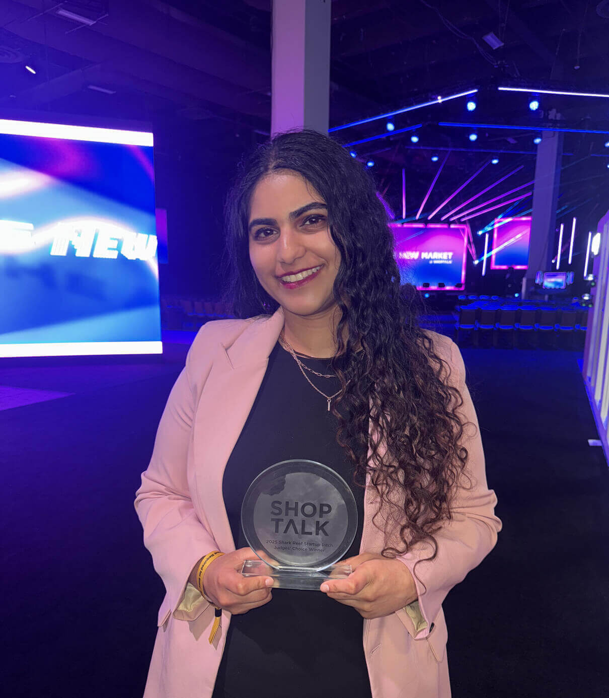 Amrita Bhasin holding the Shoptalk 2025 Shark Reef Startup Pitch Judges' Choice Winner award