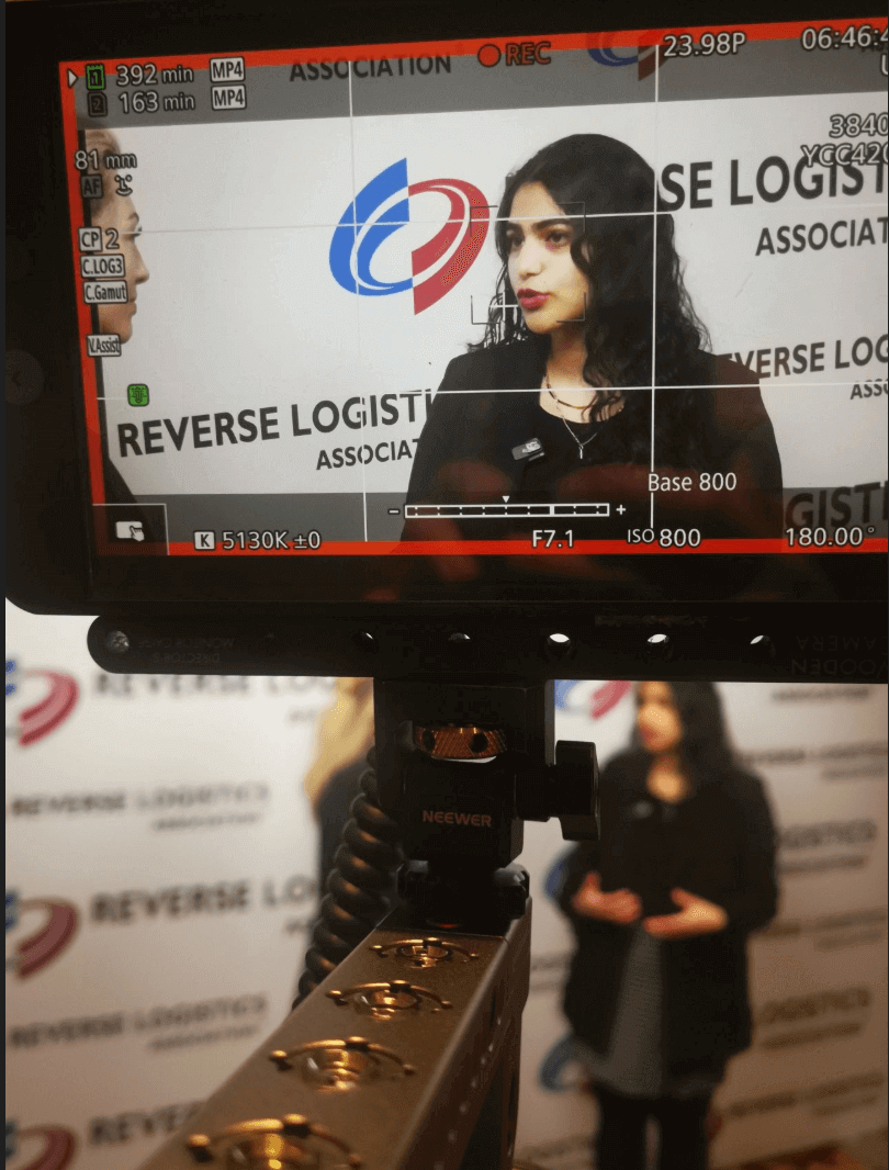 Amrita Bhasin being interviewed at the Reverse Logistics Association 2025 event, filmed through a professional camera monitor