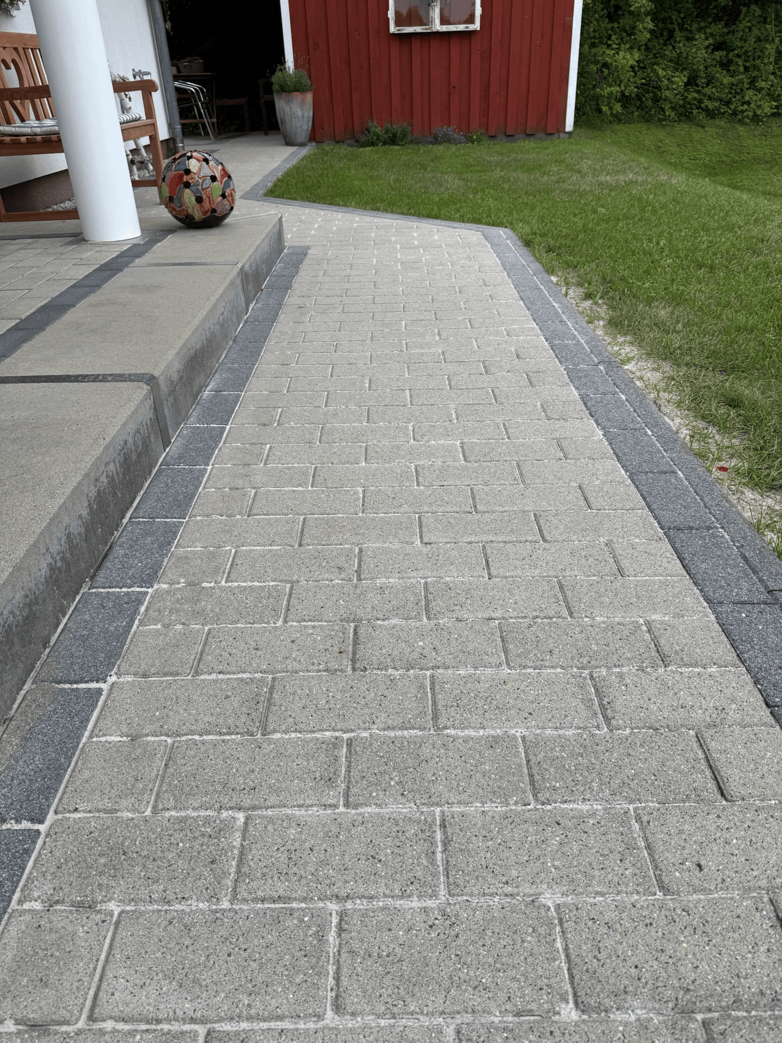 Sauber gereinigter Gehweg aus hellgrauen Pflastersteinen nach professioneller Steinreinigung
