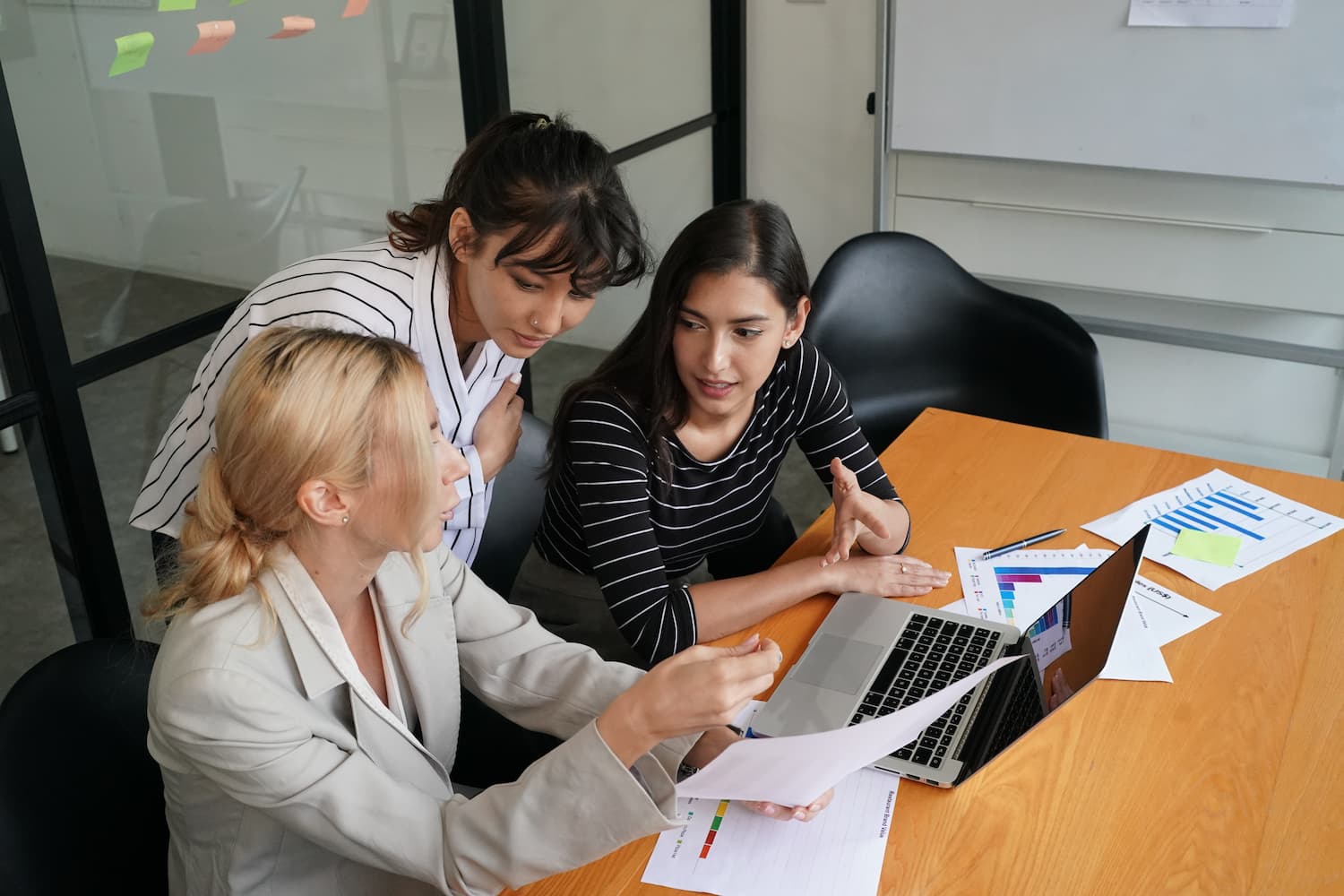 team of women huddled around office desk