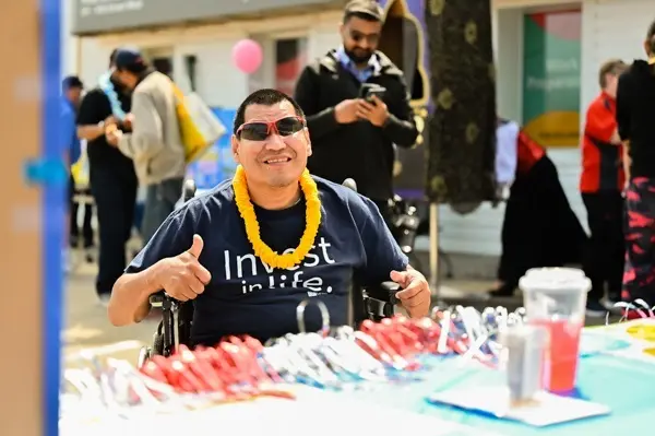 Dennis giving a thumbs up, while sitting at an event table.