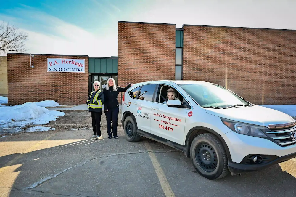 admin member and volunteer driver smiling at car