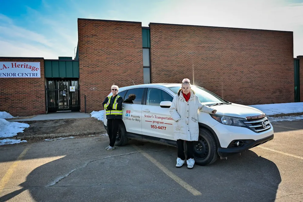 senior and volunteer driver outside of car