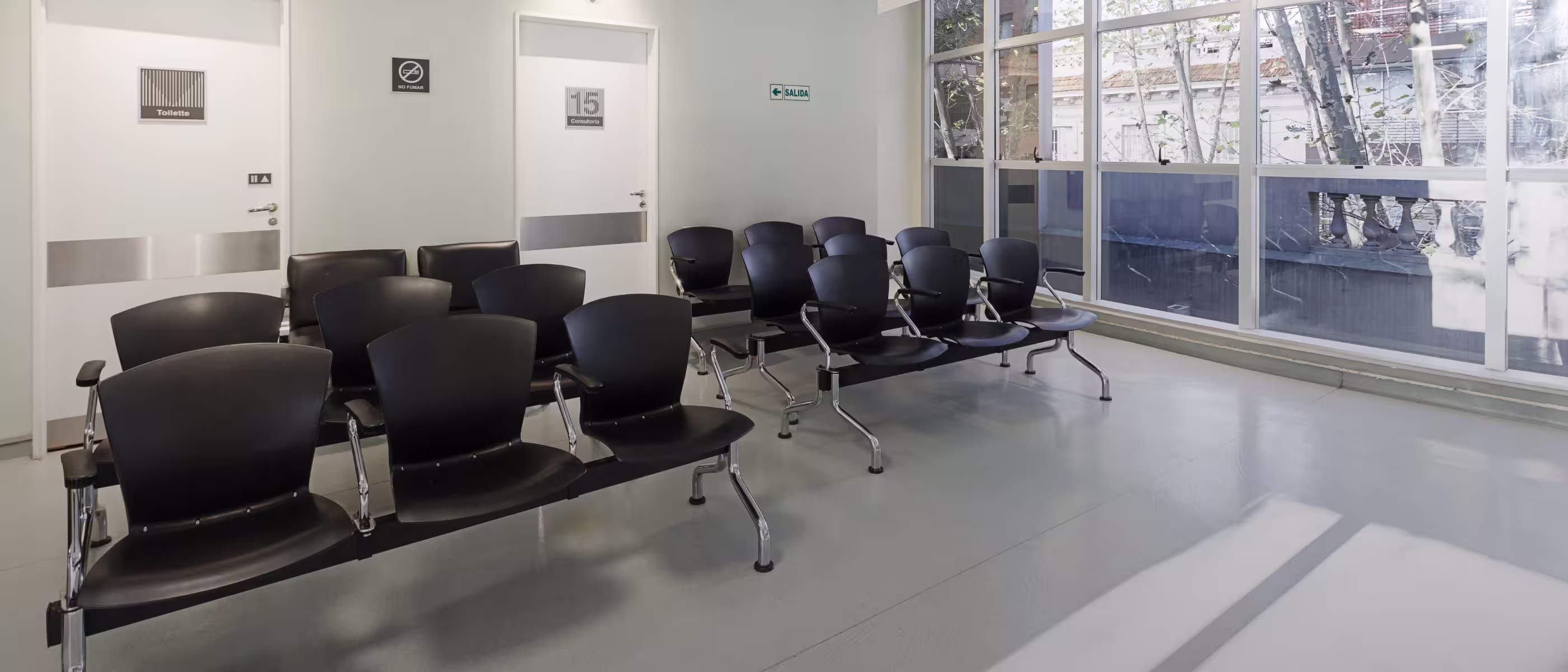 Sala de espera con sillas negras, recepcionista y cartel de campaña de gripe Medicus
