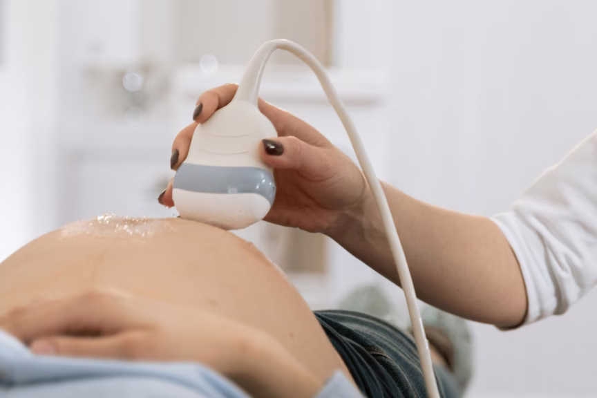 Vientre de embarazada siendo escaneado con sonda de ultrasonido en la consulta del médico