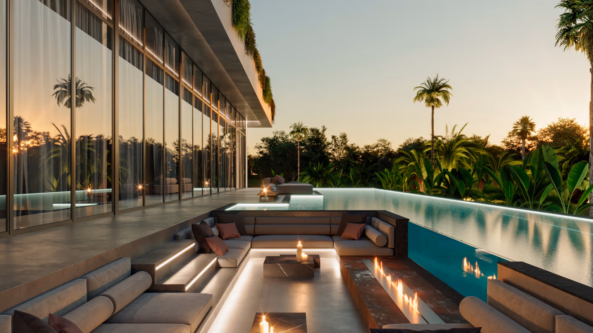 Modern outdoor sunken lounge area with cushioned seats, candles, fire feature, and infinity pool at sunset surrounded by palm trees.