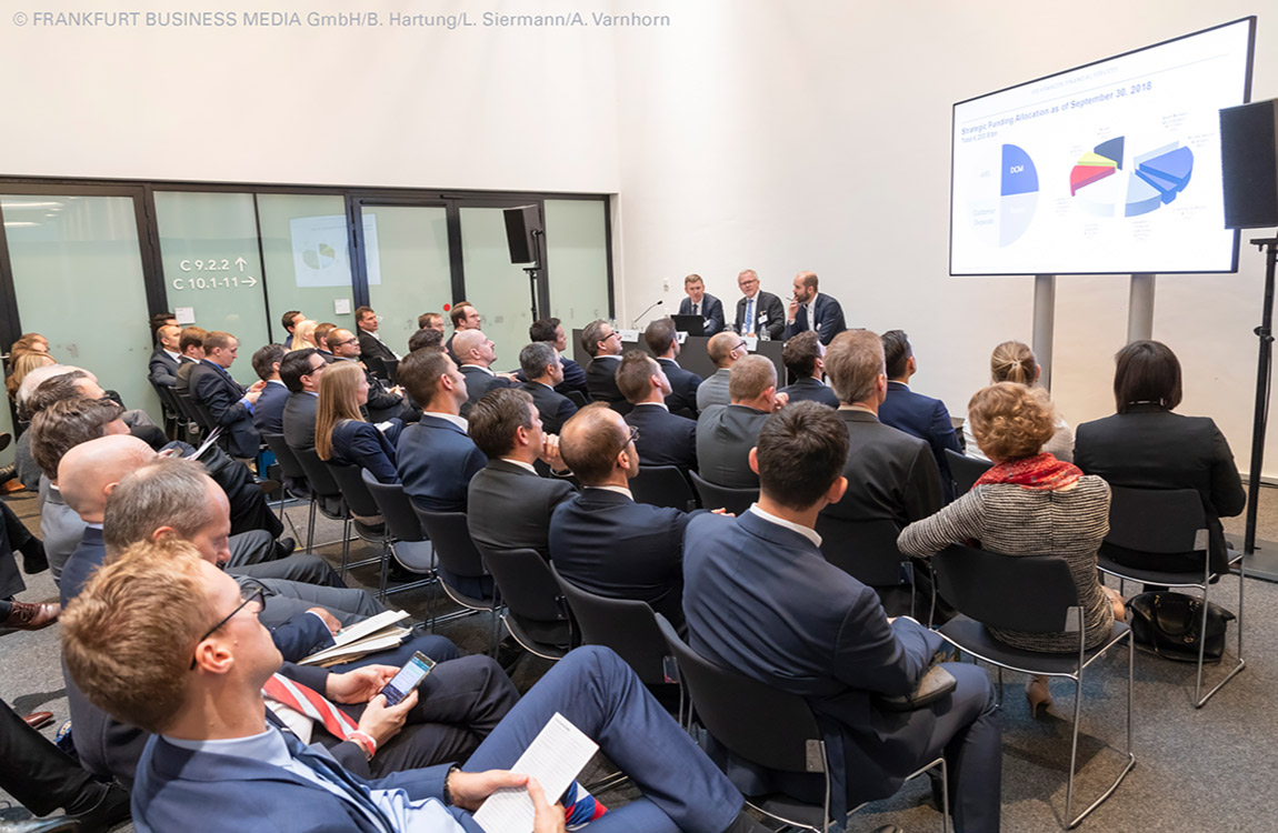 people sitting and listening to a panel discussion at a conference