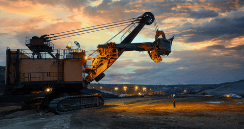 Silhouette of an excavator at a construction site during sunset