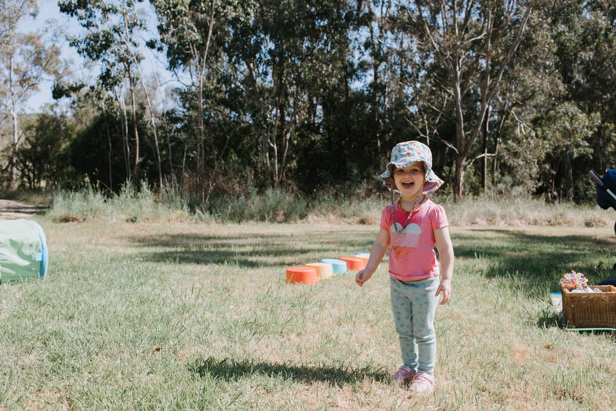 A child running outdoors on grass, playing freely.