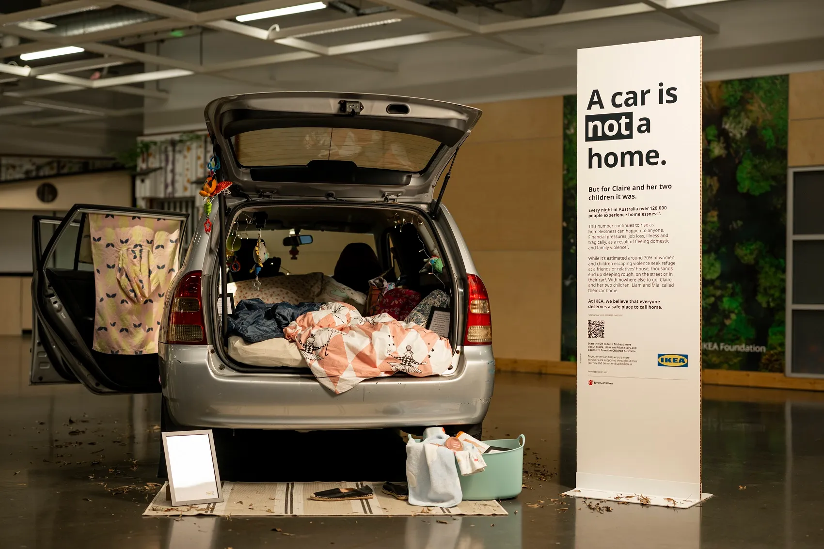 An open car boot filled with household items, displayed as part of an exhibition.