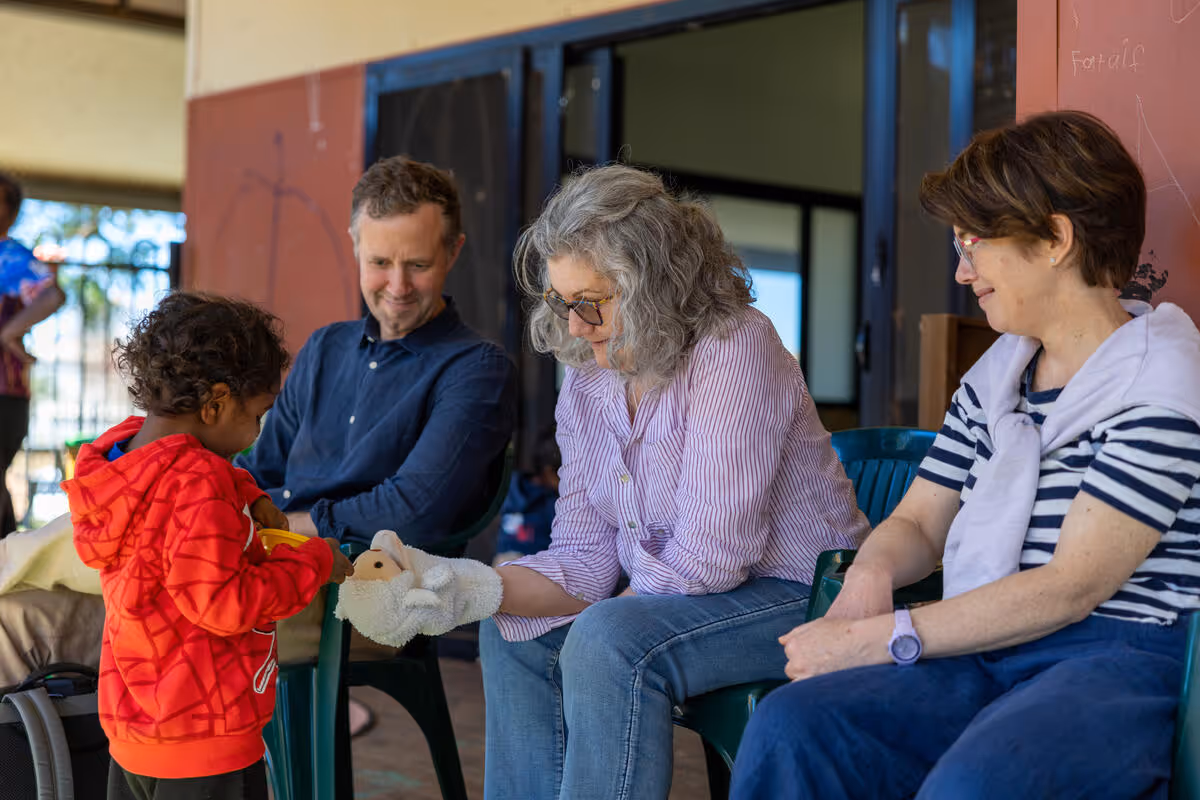 Older adults and a child sitting together indoors, sharing an activity and conversation.
