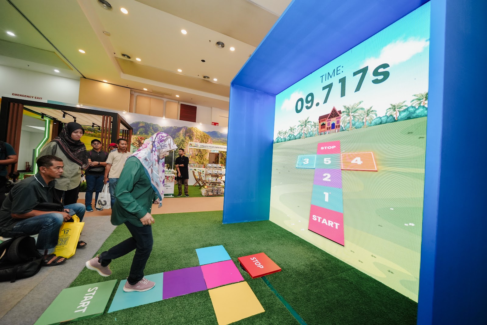 Players jumping on floor sensor pads controlling a big screen game at MAHA Malaysia