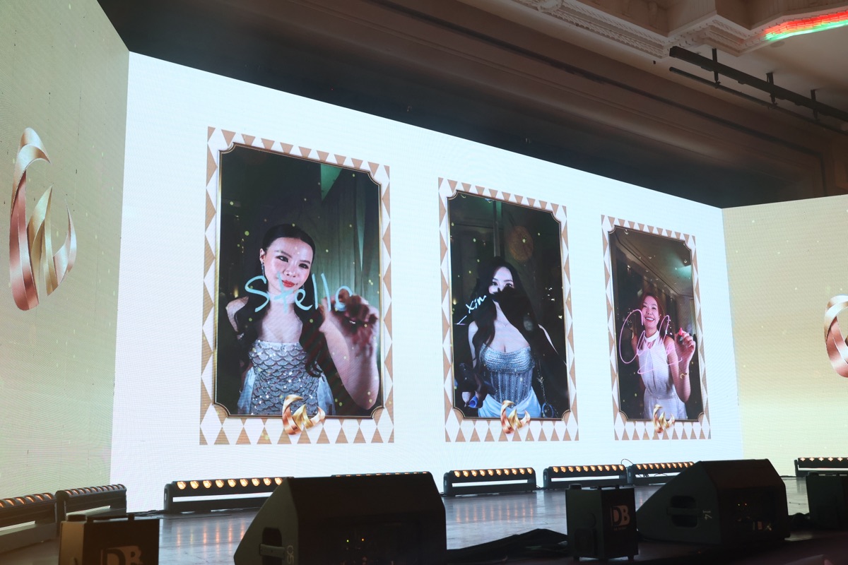 Guest portraits with handwritten signatures streaming live onto a ballroom LED wall from a glass photo booth