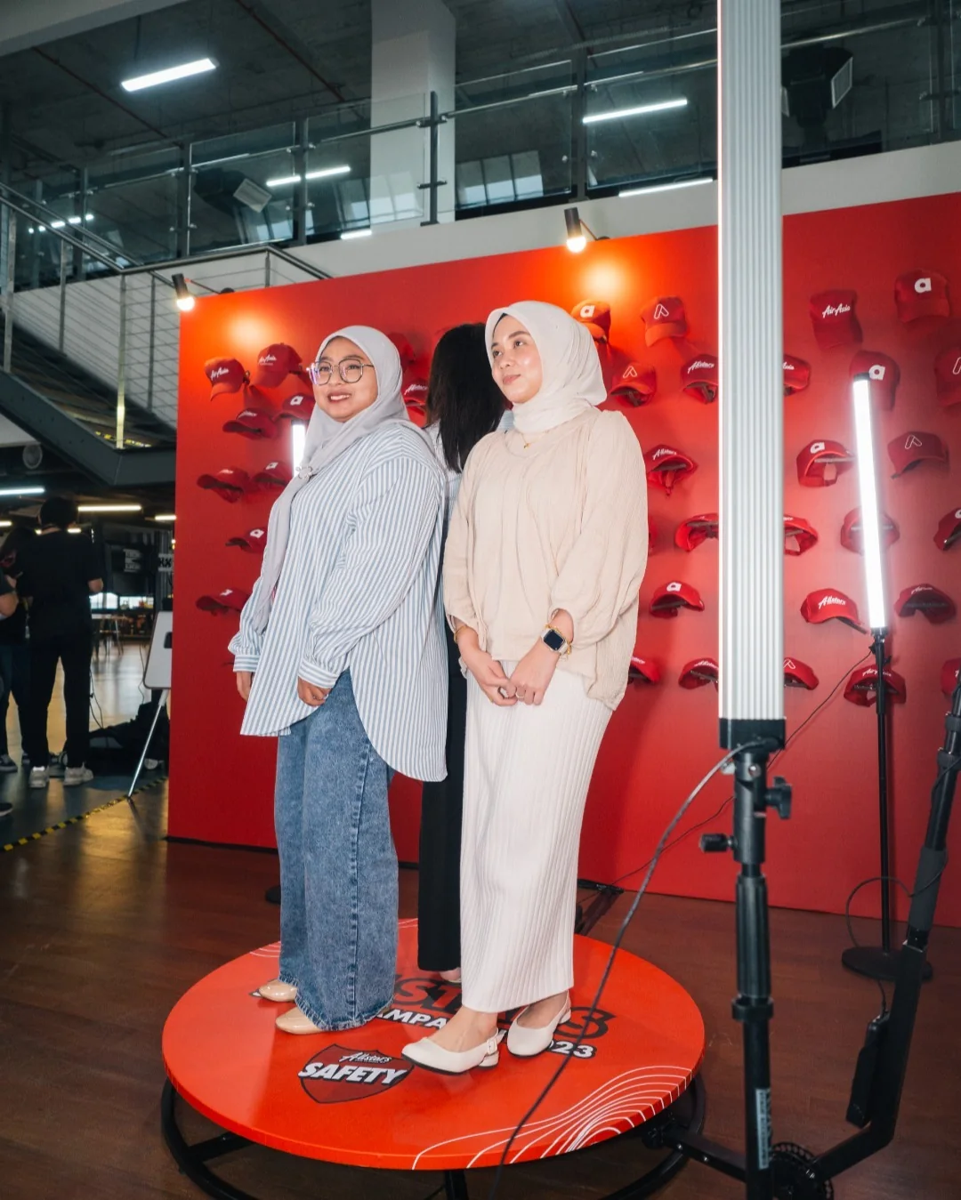 Two guests on the 360 spin photo booth platform with the camera arm and light tubes at a corporate safety day