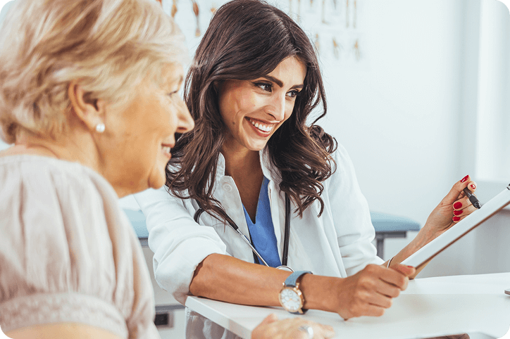 A smiling female doctor reviews treatment and payment options with an older female customer.