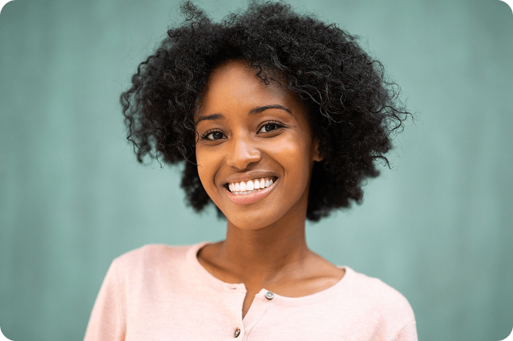 A smiling woman in a light pink shirt poses confidently, representing a consumer exploring Klarna alternatives.