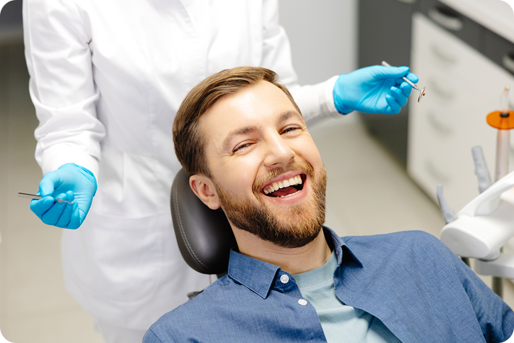A smiling patient relaxes in a dental chair after being referred by a friend through a dental referral program.