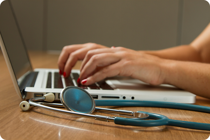 Hands typing on a laptop next to a stethoscope, representing medical loans and healthcare financing options.
