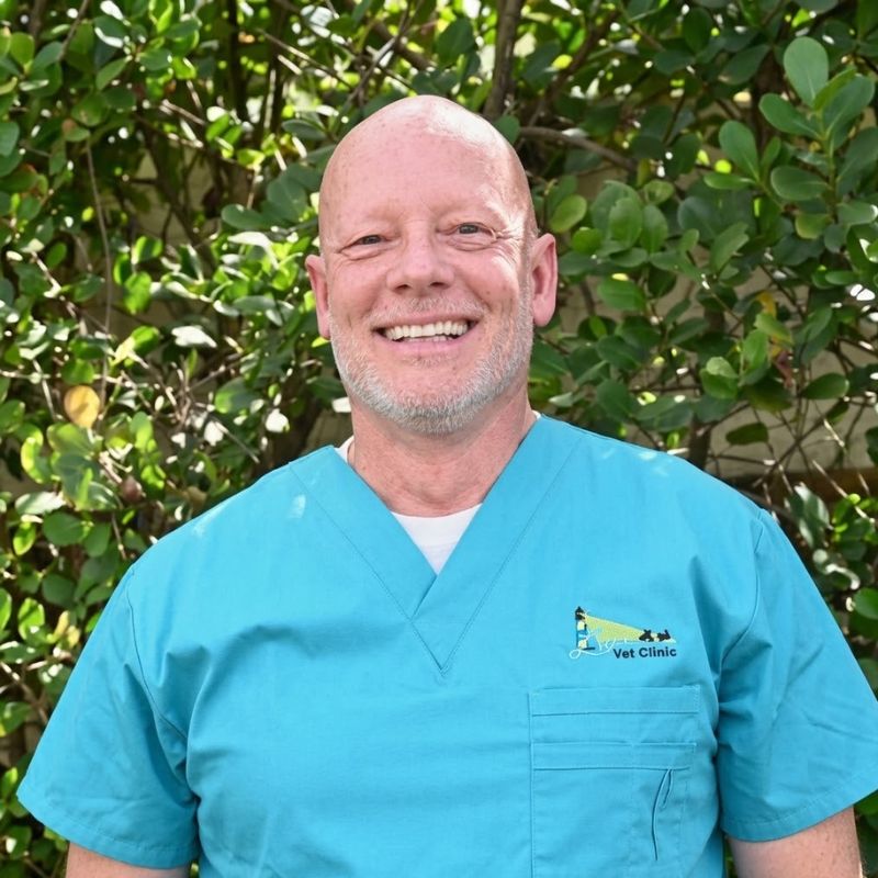 Mike Woodward, Vice President of Administration at Lighthouse Pet Clinic, smiling in scrubs outdoors.
