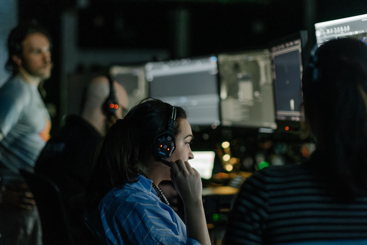 Member of a virtual production stage team sits in front of monitors, wearing a headset