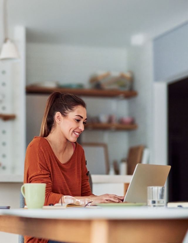 A smiling woman sitting at a laptop, shown beside a digital invoice approval panel with line items, vendor details, and Approve/Reject/Review buttons
