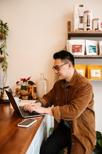 A man reviews budget data on a laptop while red “Over Budget” and spending charts appear on screen.