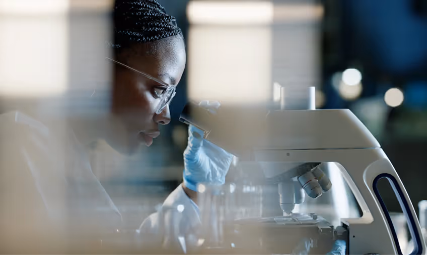 A lady uses a microscope in a lab. 