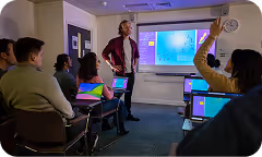 The picture of a classroom, a student raises their hand for the teacher.