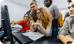 A group of people working on a PC in a class setting.
