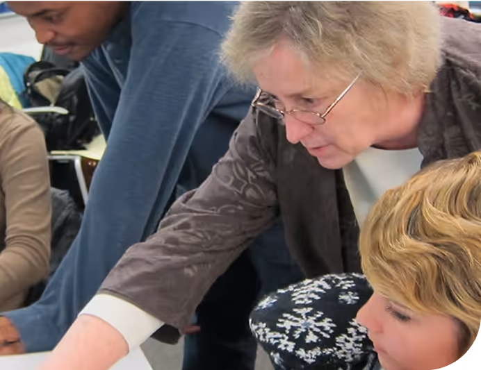 A group of people work on a project in a schoolroom setting.