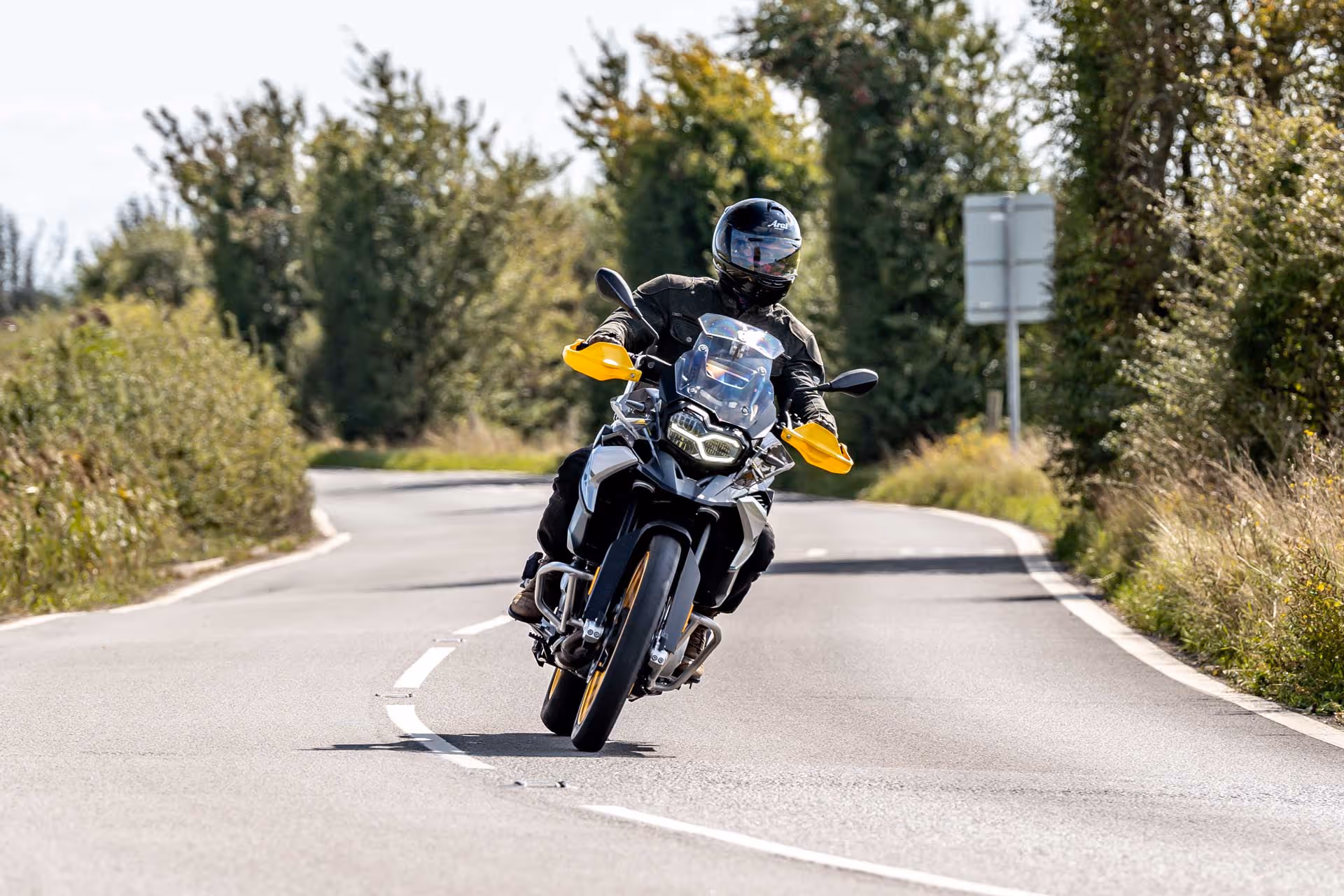 A person wearing a helmet rides a motorcycle on a curvy road.