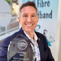 A person smiling and holding a trophy for "Best Consumer ISP" at the ISPA Awards 2024.