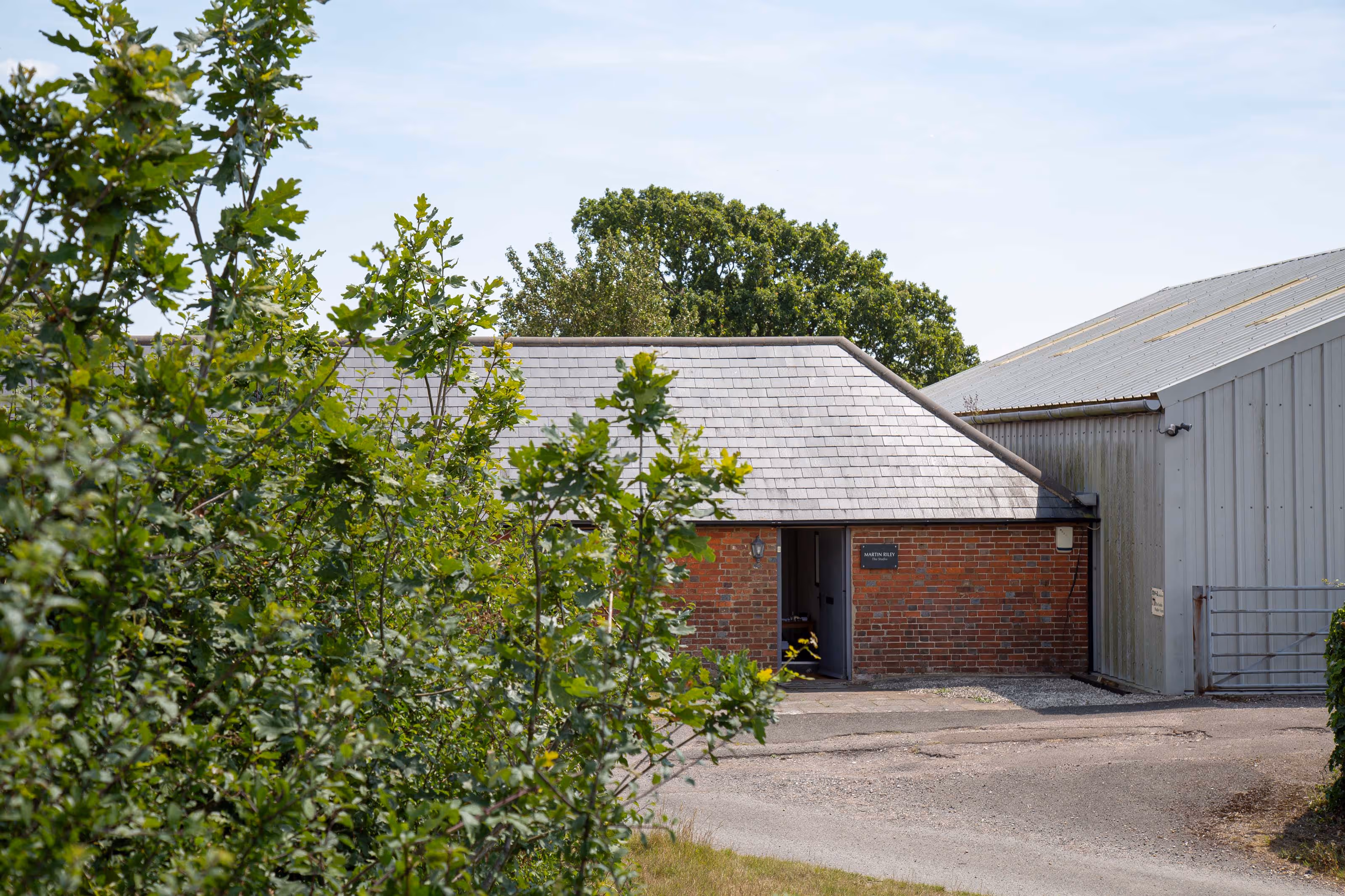 A brick building with a slate roof is partially visible behind green bushes.