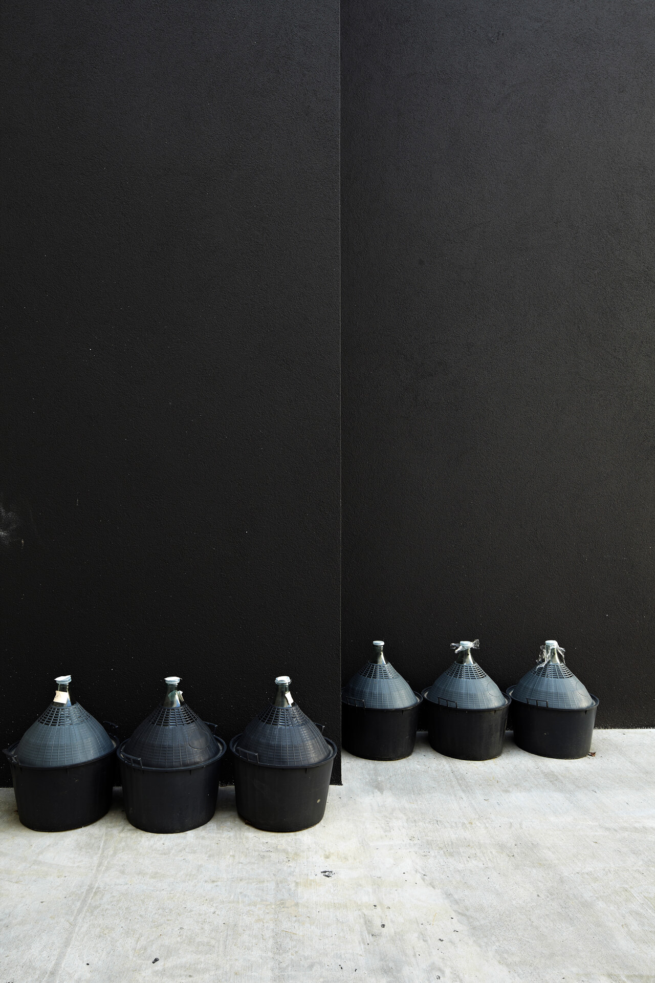 Loimer Kegel Kunstobjekt in Schwarz an schwarzer Wand lehnend