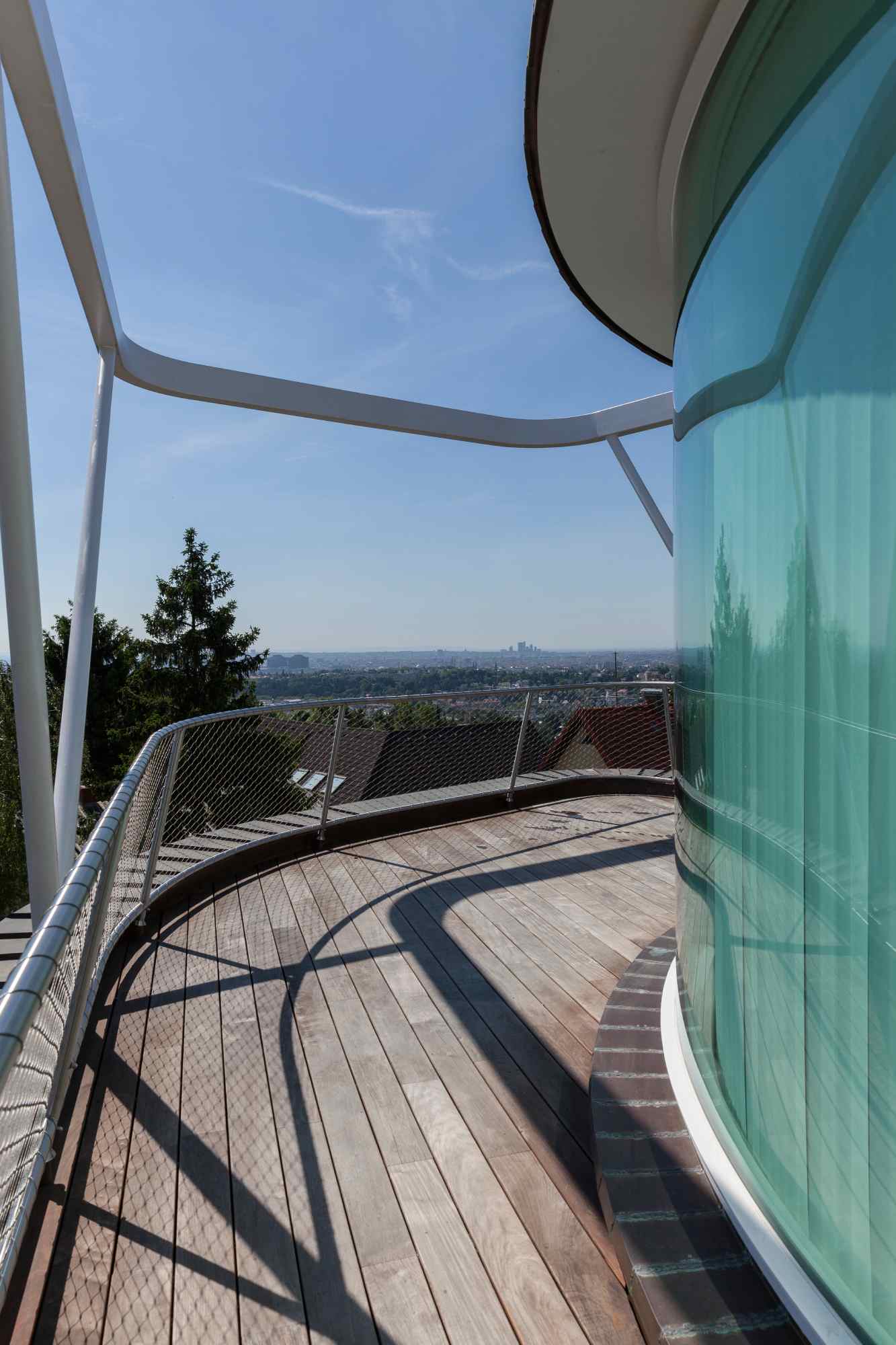 Holzterrasse mit Glasfront und Blick ins Grüne.