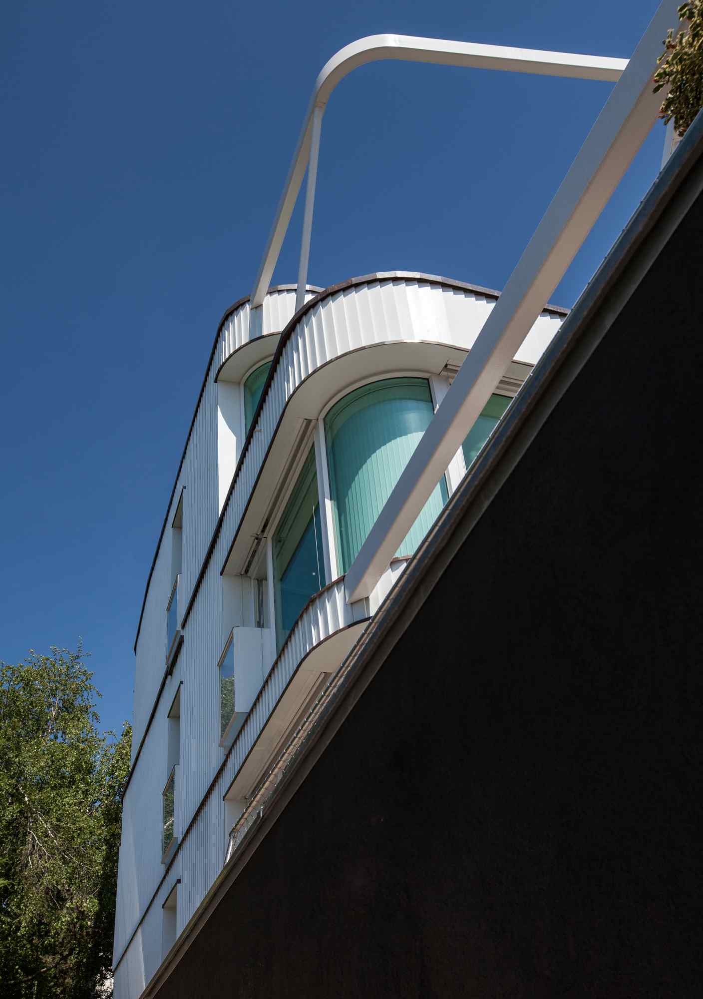 Dynamische Seitenansicht mit Glasfassade und kurviger Architektur.