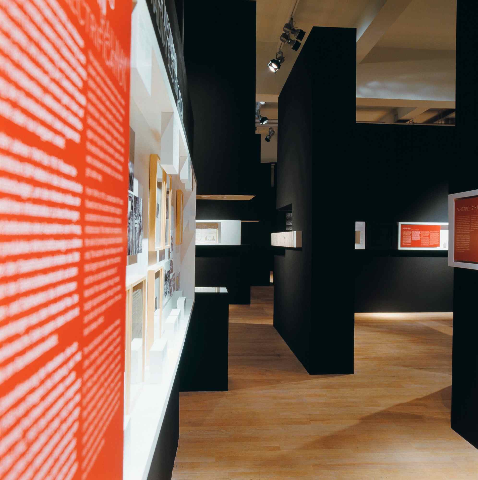 Blickachse durch Ausstellung mit roter Wand und Exponaten