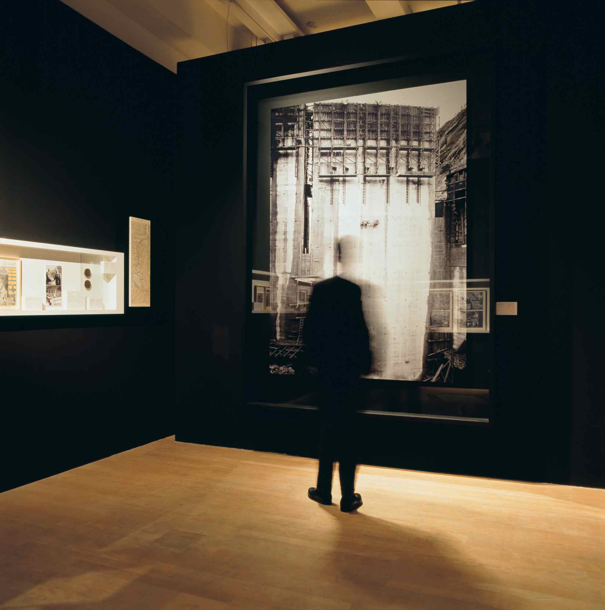 Besucherin vor großformatigem Wandbild in dunklem Raum