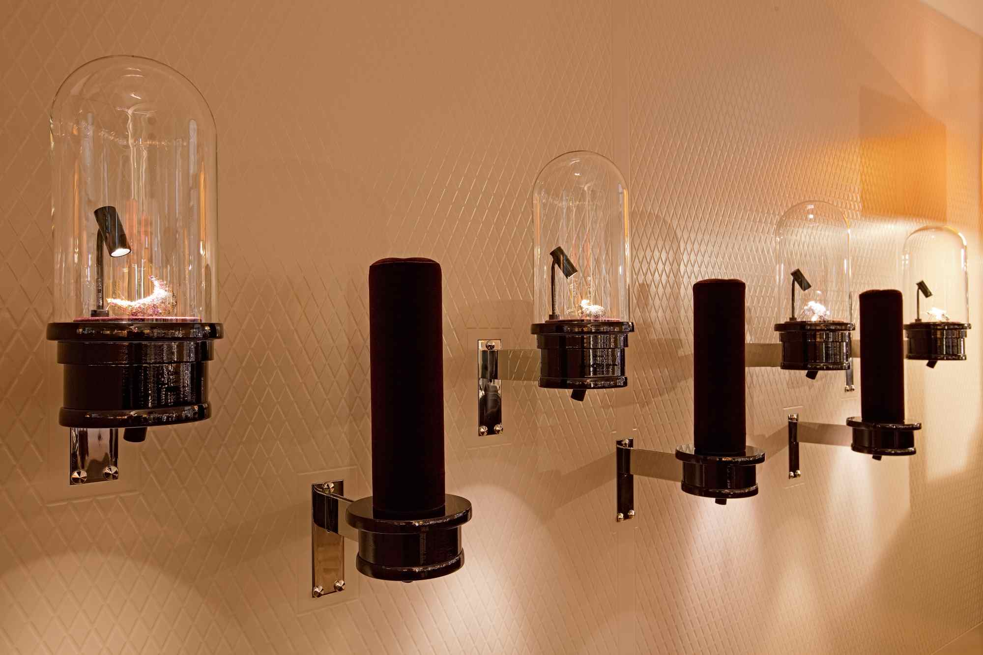 Wandleuchten mit Glashauben an cremefarbener Wand.