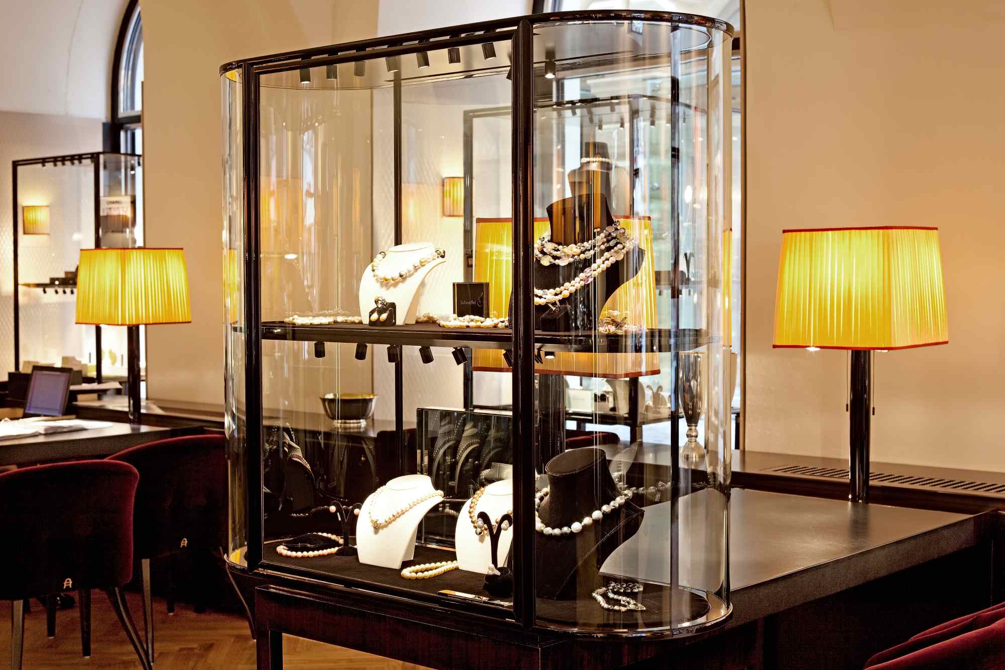 Freistehende Vitrine mit Schmuckstücken, begleitet von Stehleuchte.