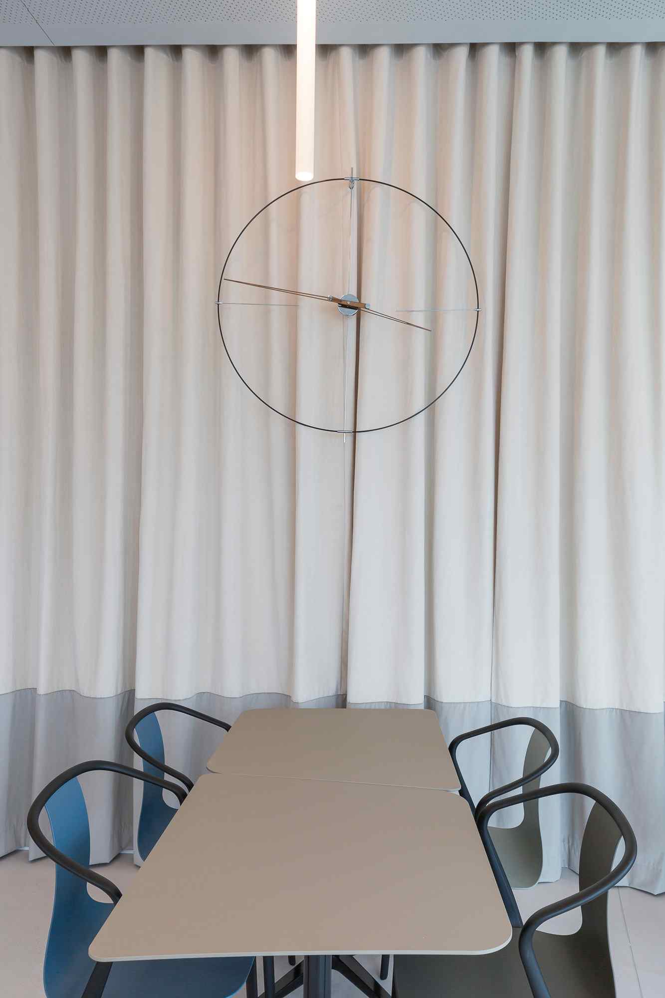 Tisch mit Stühlen vor Vorhang und dekorativem Kreisobjekt