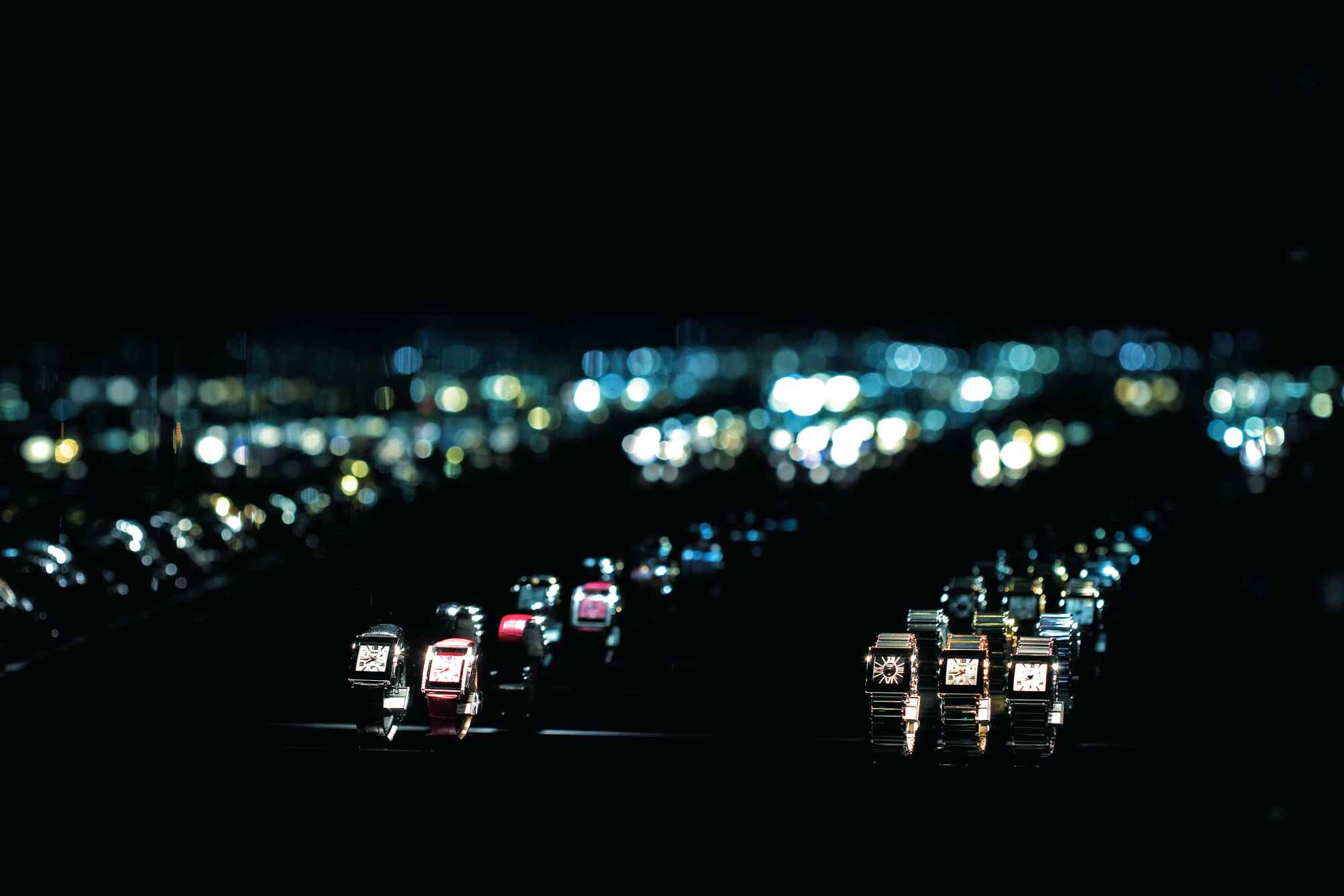 Dunkler Raum mit beleuchteten Uhrenvitrinen in Reihen