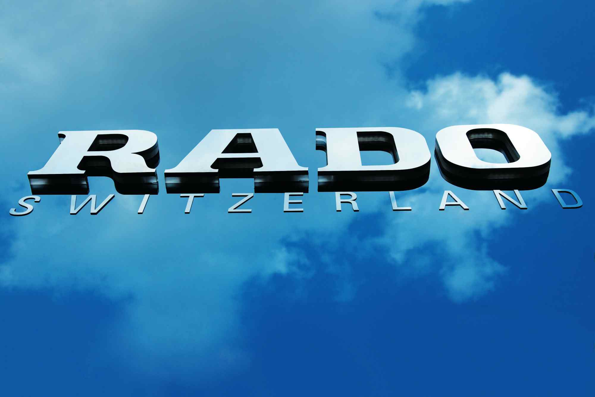 RADO-Logo vor blauem Himmel, frontal fotografiert