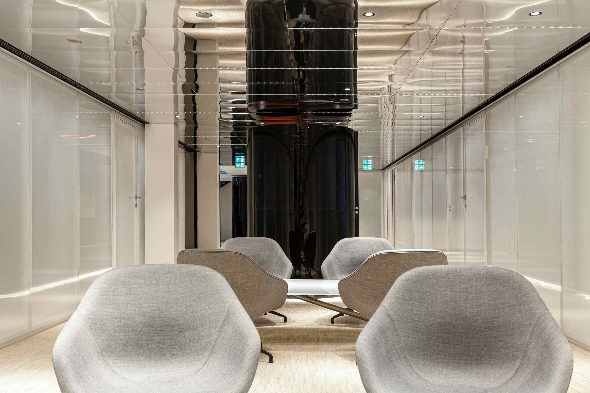 Loungebereich mit zwei grauen Sesseln und Glaswänden