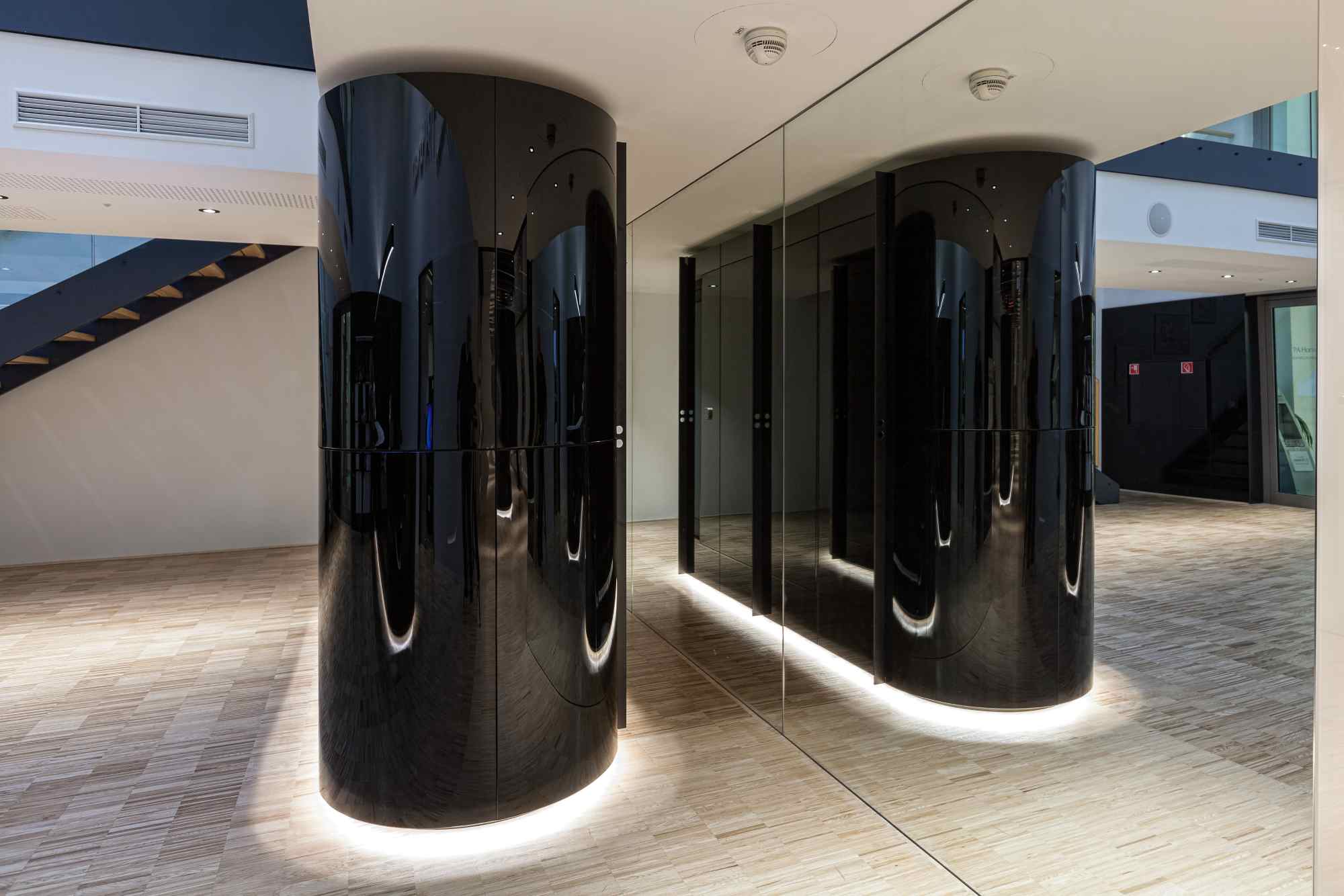 Eingangszone mit zwei schwarzen Säulen und Natursteinboden