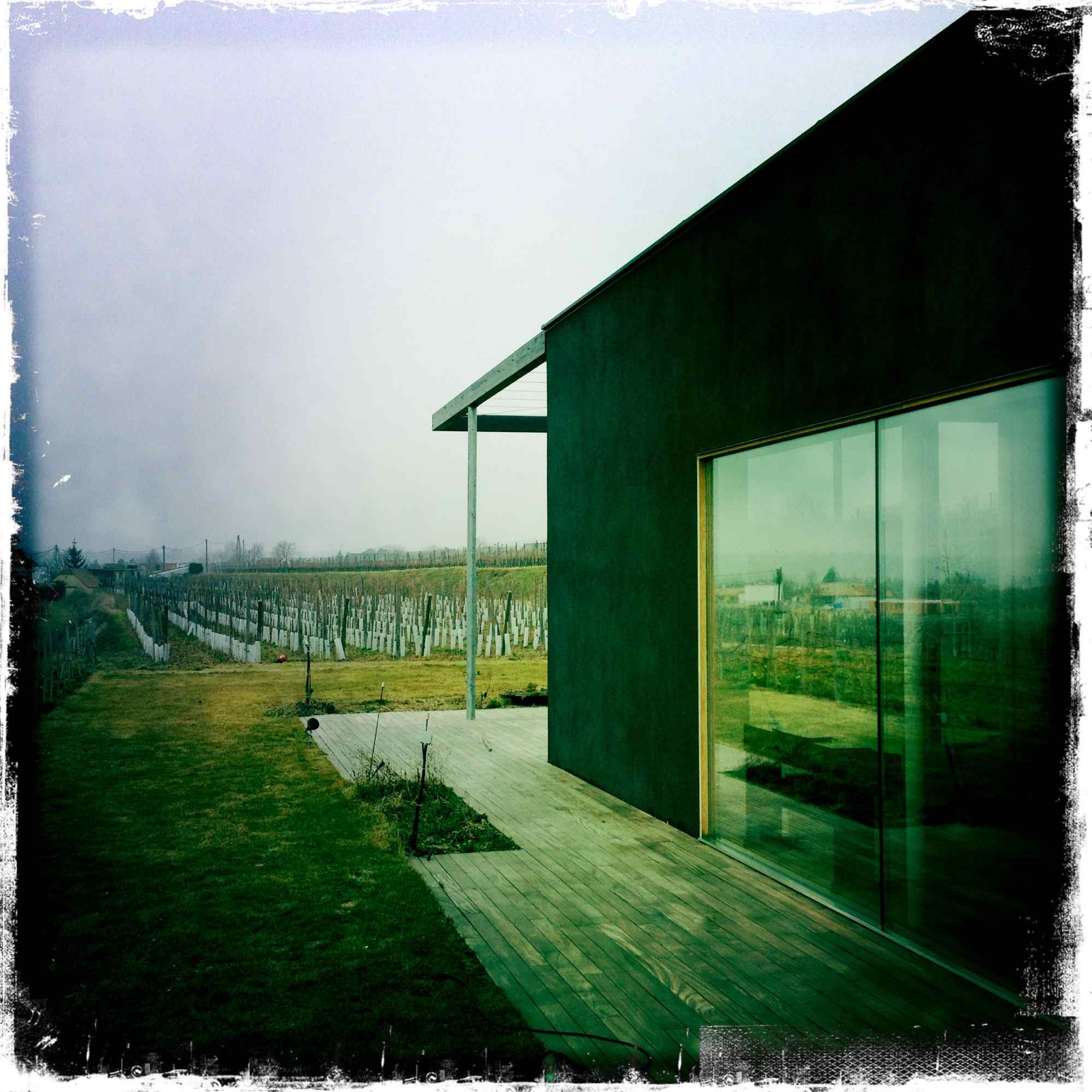 Seitliche Ansicht mit durchgehender Glasfront und Holzdeck